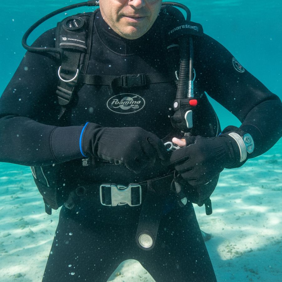 Buceador practicando la suelta del lastre en agua clara con chaleco y cinturón bien visibles.